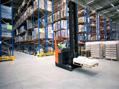 worker-operating-forklift-machine-and-relocating-goods-in-large-warehouse-center.jpg