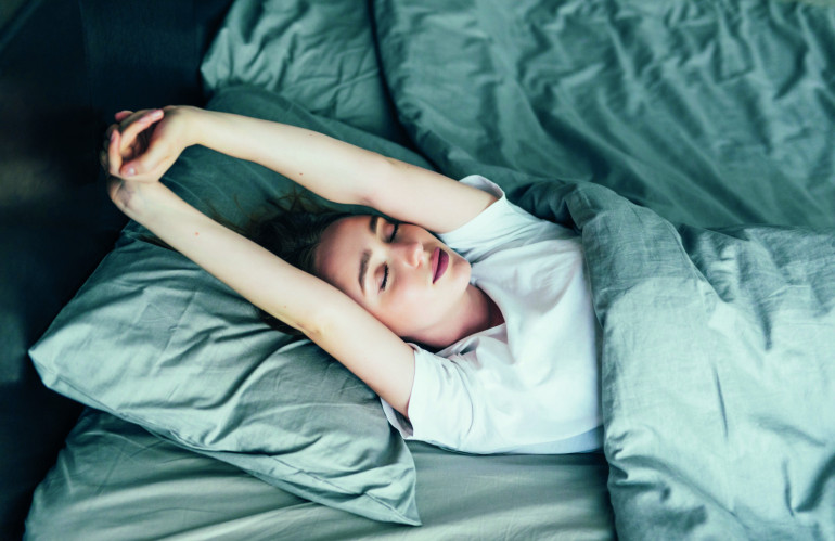 attractive-woman-stretching-in-the-morning-and-is-smiling-in-her-bed.jpg