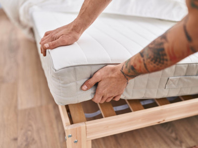 jovem-segurando-colchao-no-quarto.jpg